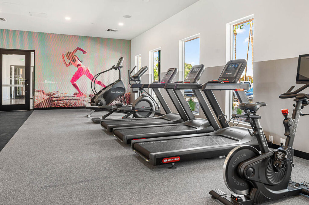 Indoor gym with 3 treadmills and 2 stationary bikes, and 4 windows
