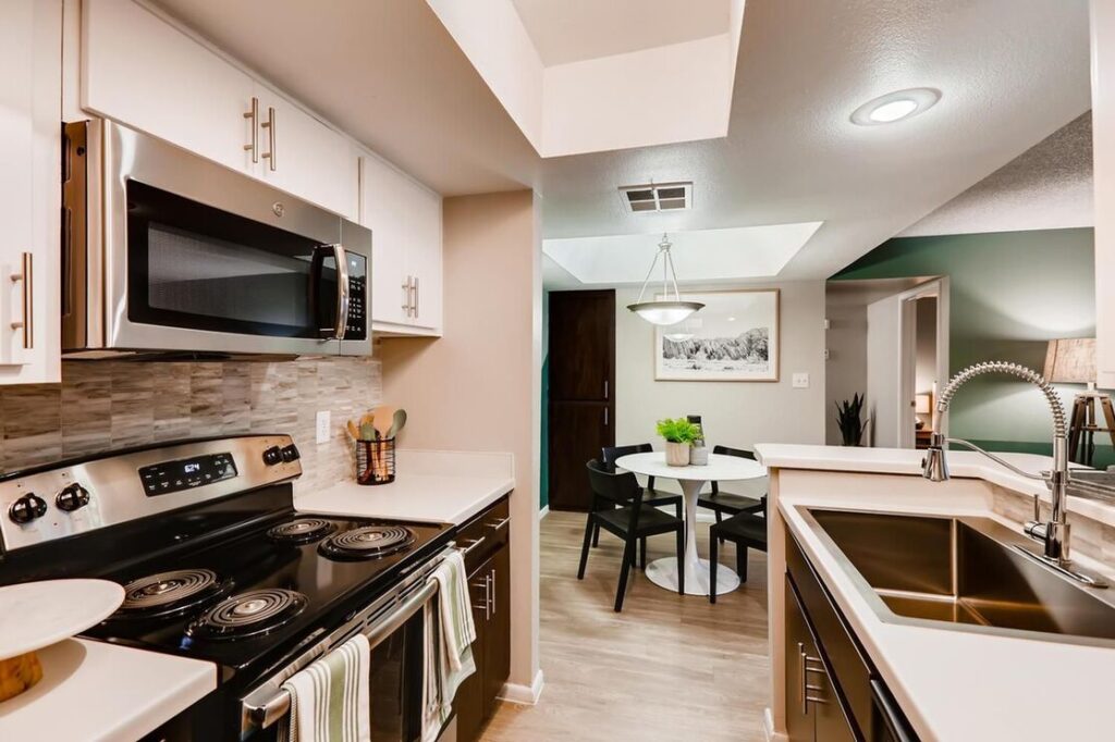view of kitchen and stainless steel and black appliances, electric stove and sink with slight view of dining area with white circle table