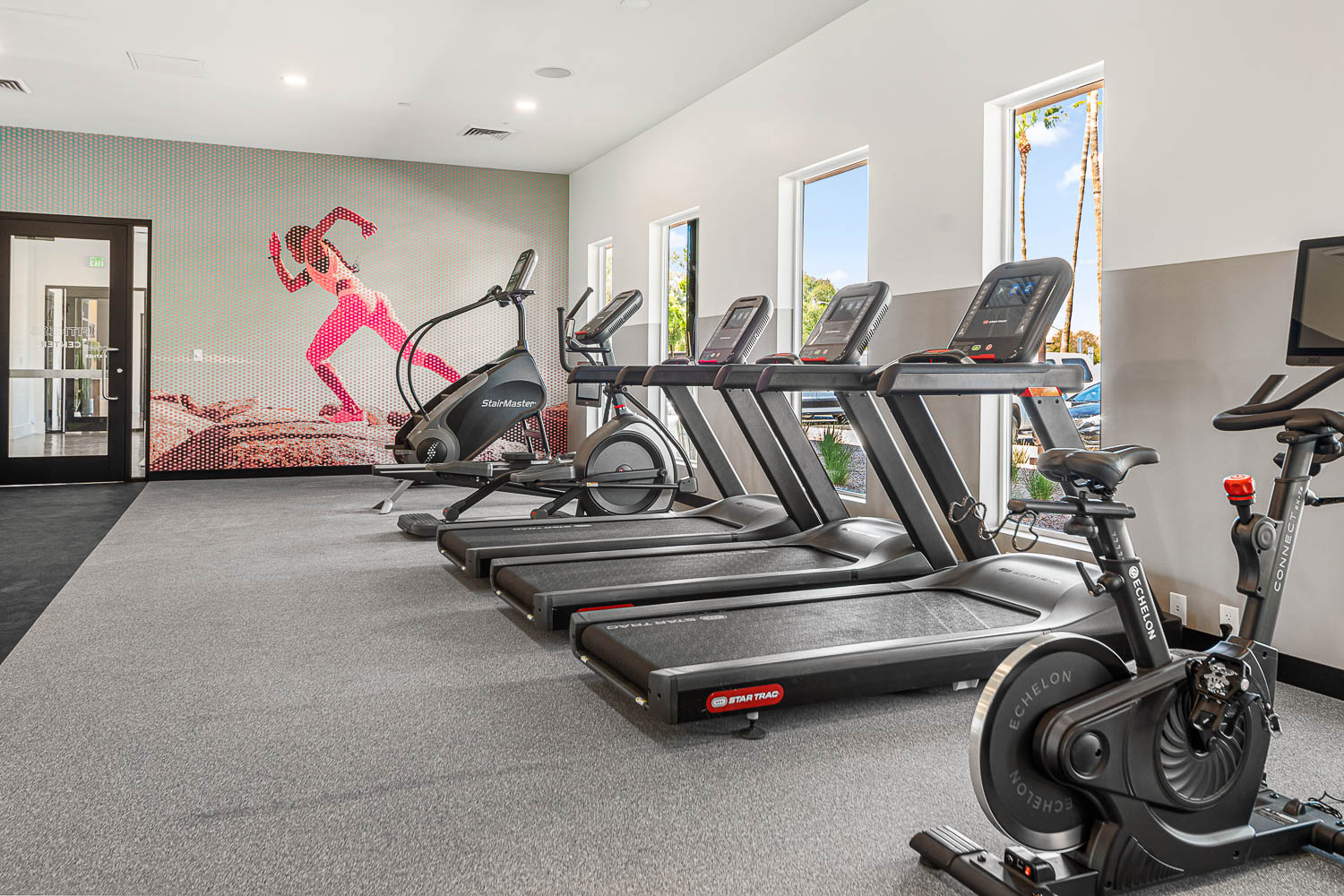 indoor gym with 3 treadmills and 2 stationary bikes, an 4 windows